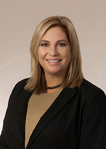 headshot of a lady wearing a tan blouse with black blazer and blonde hair