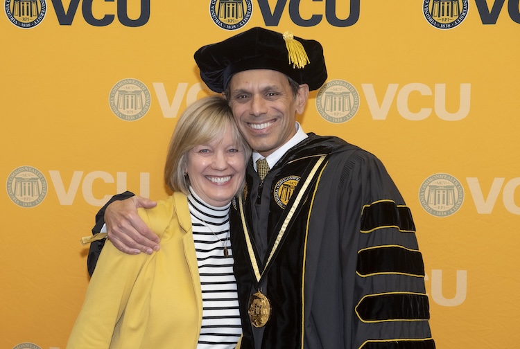 Woman standing next to man in graduation outfit for a professor