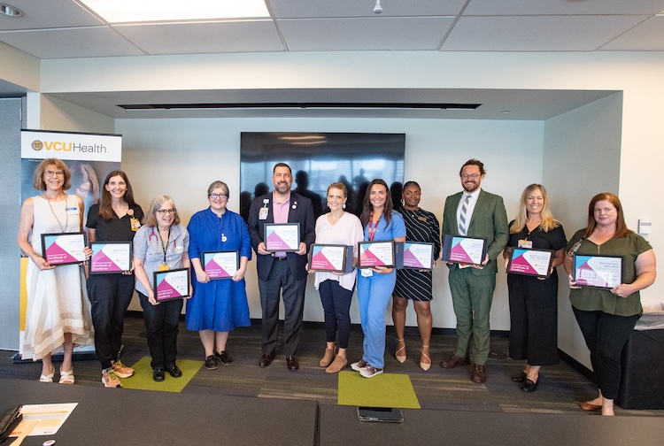 Large group of awardees stand together with flowers