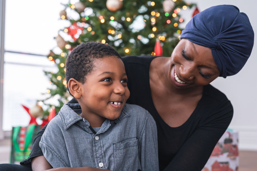 Mother and son enjoying Christmas in front of their tree