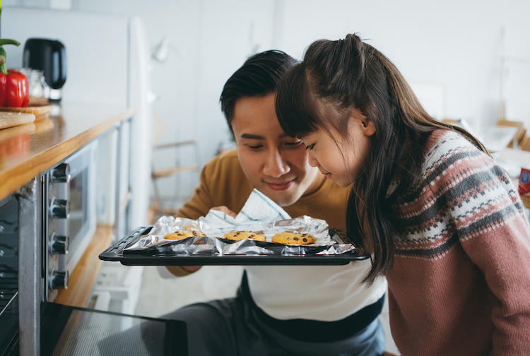 Father and daughter smelling fresh baked cookies from the oven.