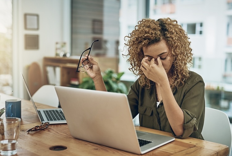 young woman suffering from stress while using a computer at her work desk