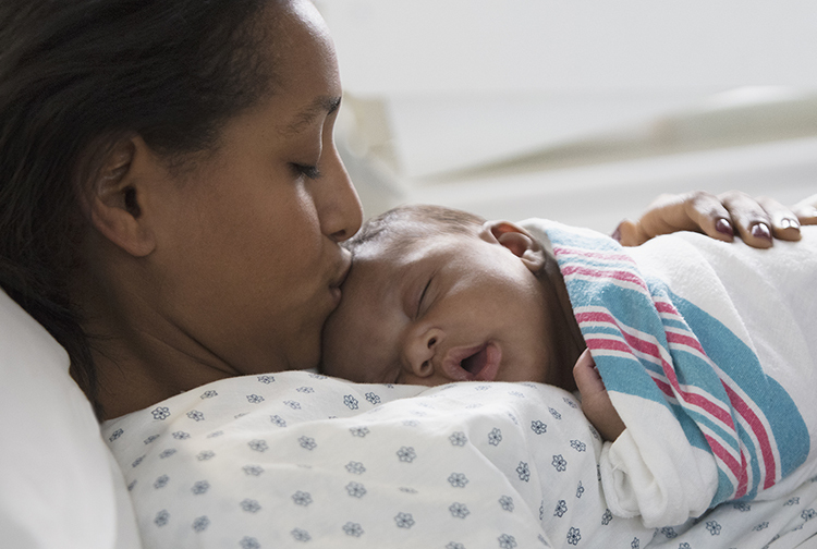 mother kissing the head of a newborn