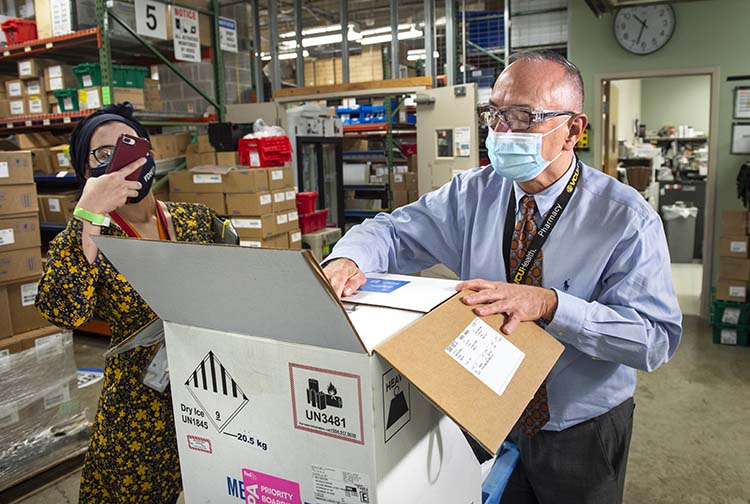 Rodney Stiltner opening box containing COVID-19 vaccine