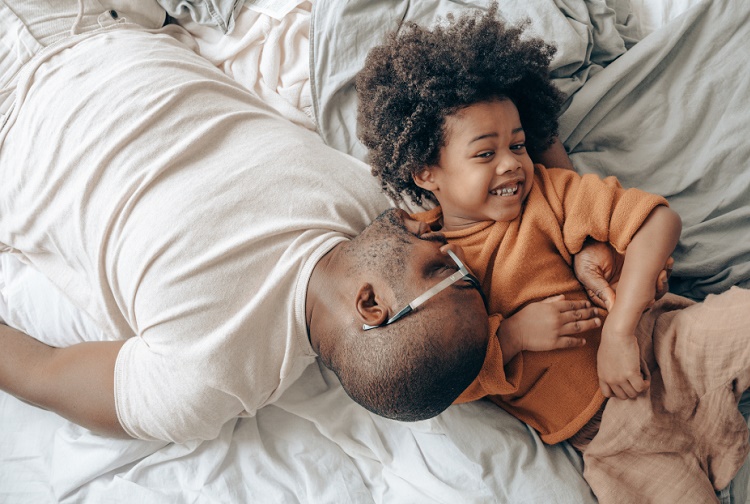 Father and son lying beside each other on a bed and smiling